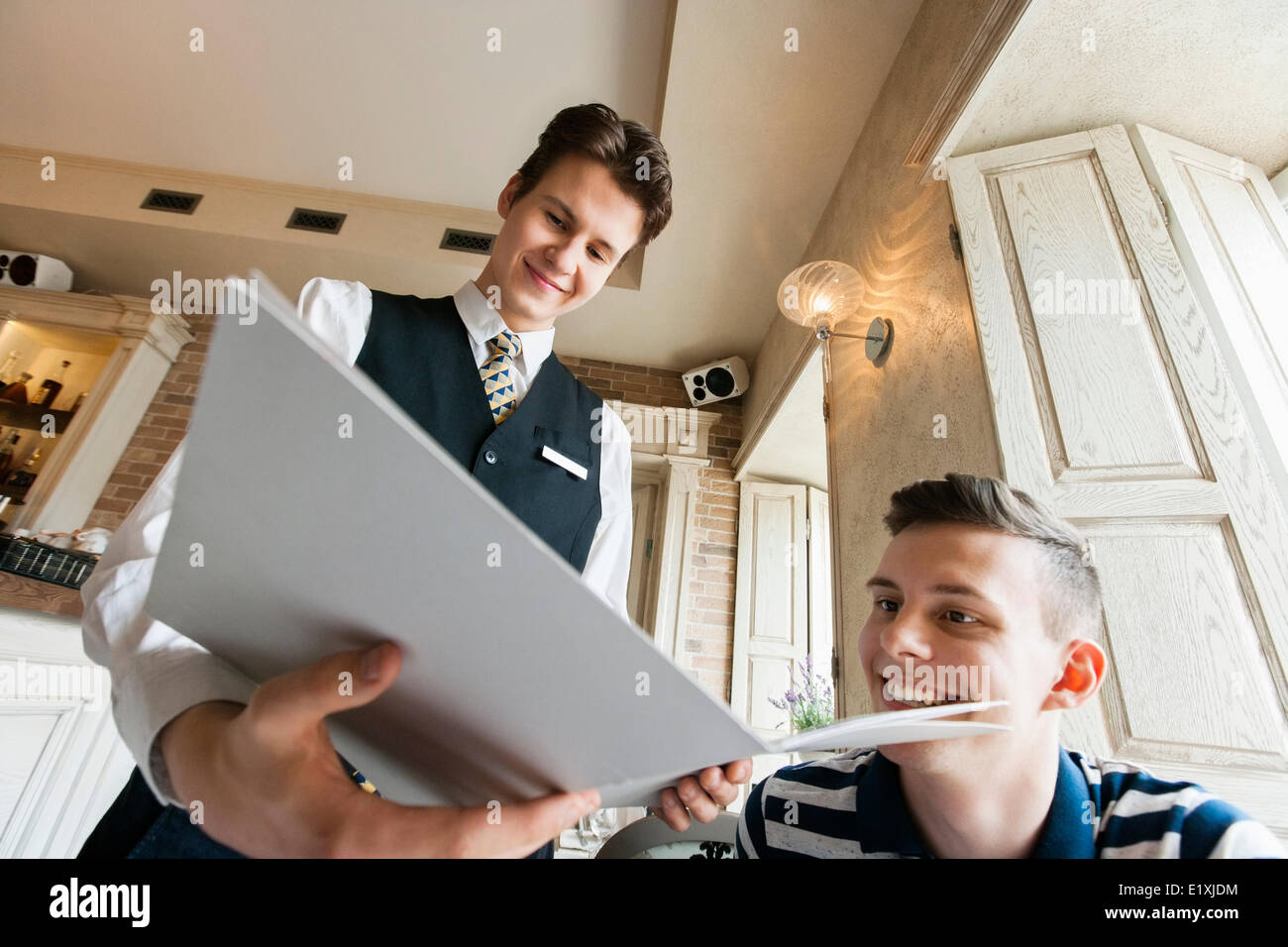 Low angle view of waiter showing menu to male customer in restaurant Stock Photo