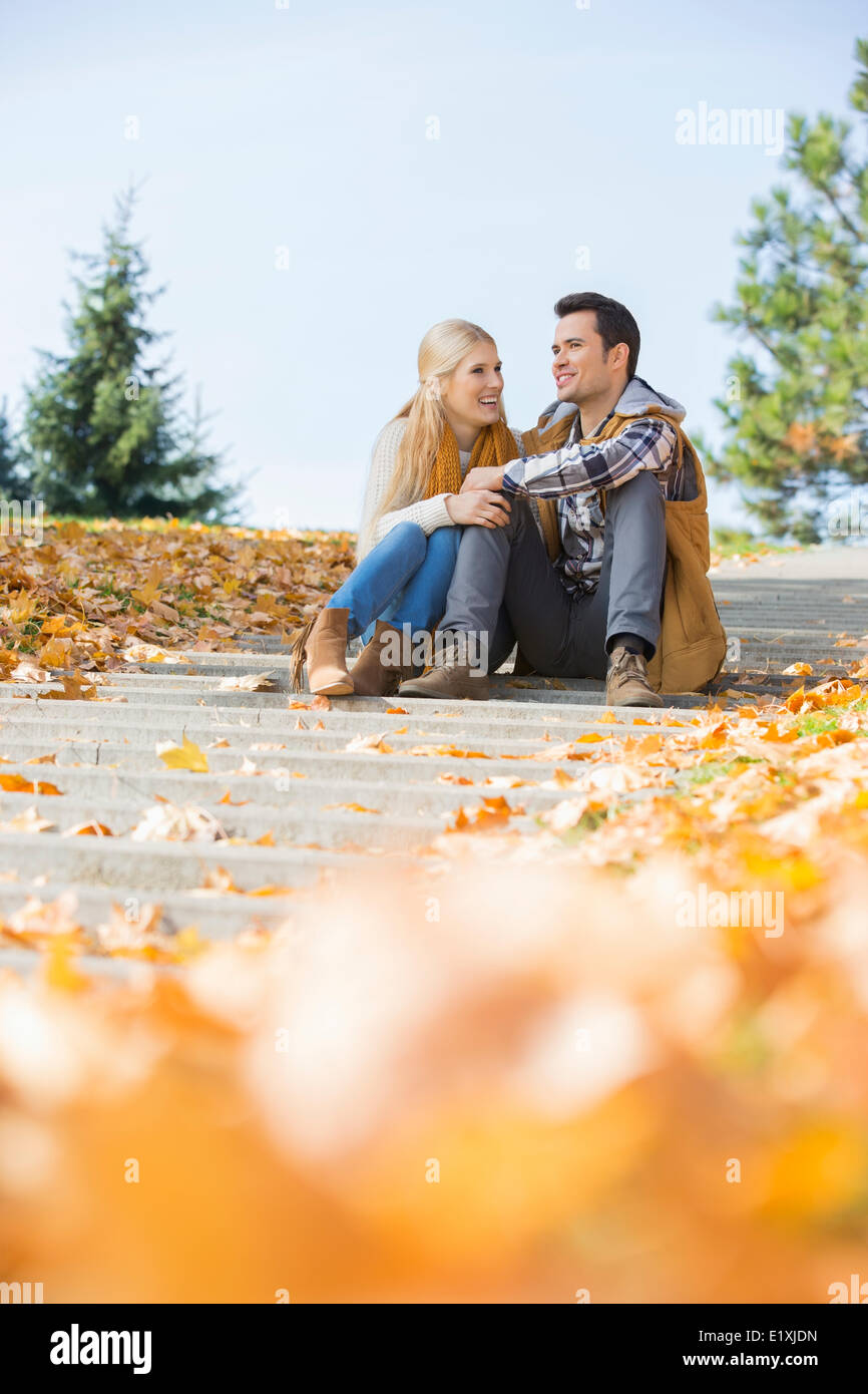 Happy young couple sitting on steps in park Stock Photo - Alamy