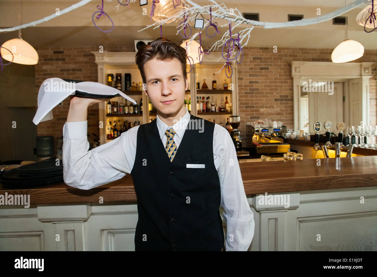 Portrait of confident waiter carrying serving tray in restaurant Stock