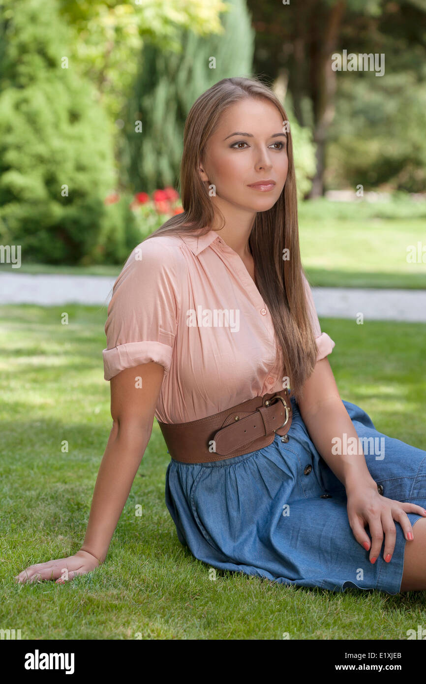 Beautiful young woman sitting in park Stock Photo - Alamy
