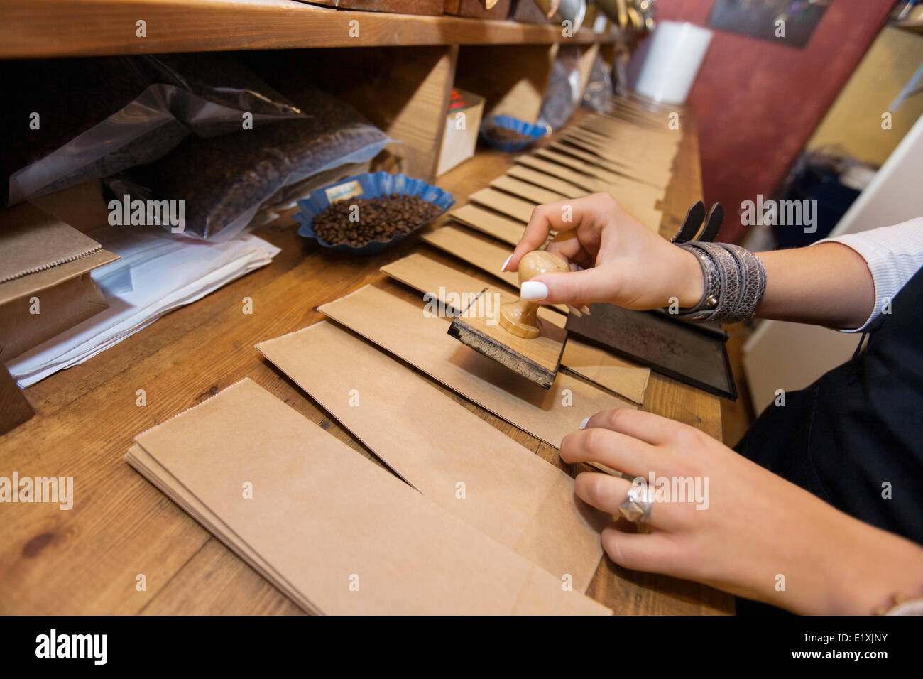Cropped image of salesperson stamping paper bags at coffee store Stock Photo