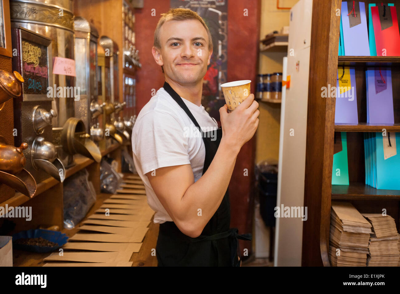Portrait of male salesperson holding disposable coffee cup in store Stock Photo
