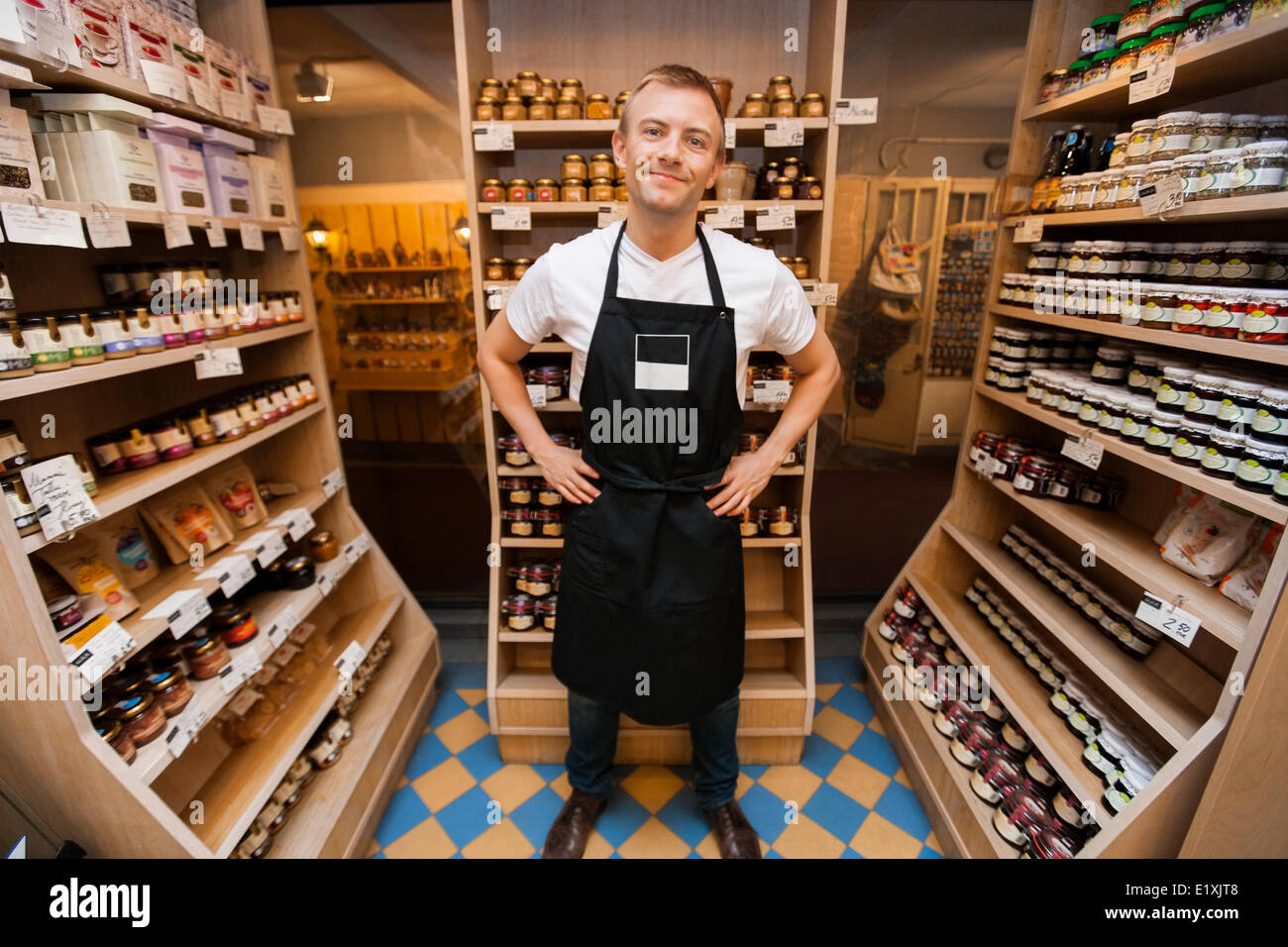 Full length portrait of mid adult salesman standing hands on hips in grocery store Stock Photo