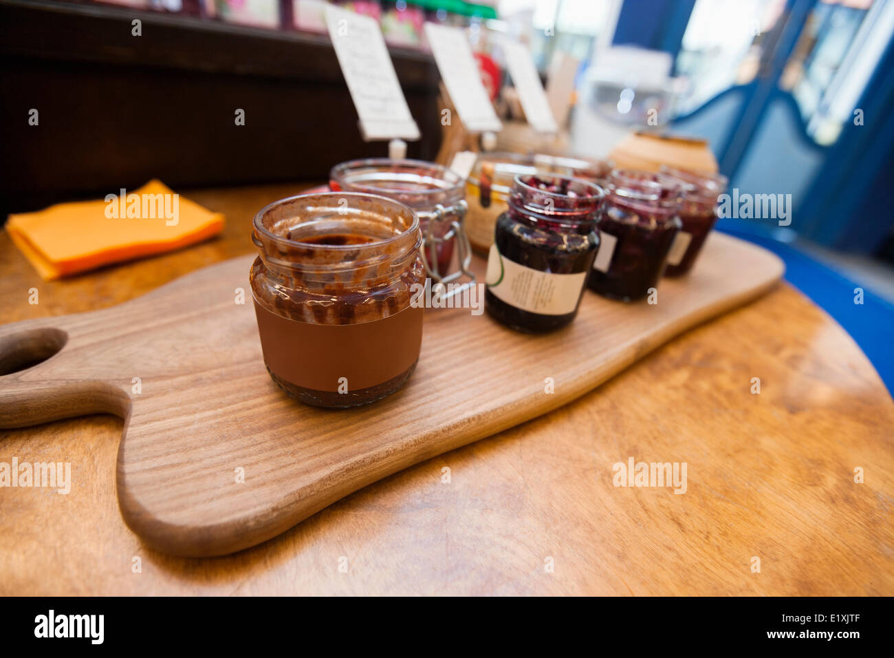 Jars of preserves on cutting board in grocery store Stock Photo