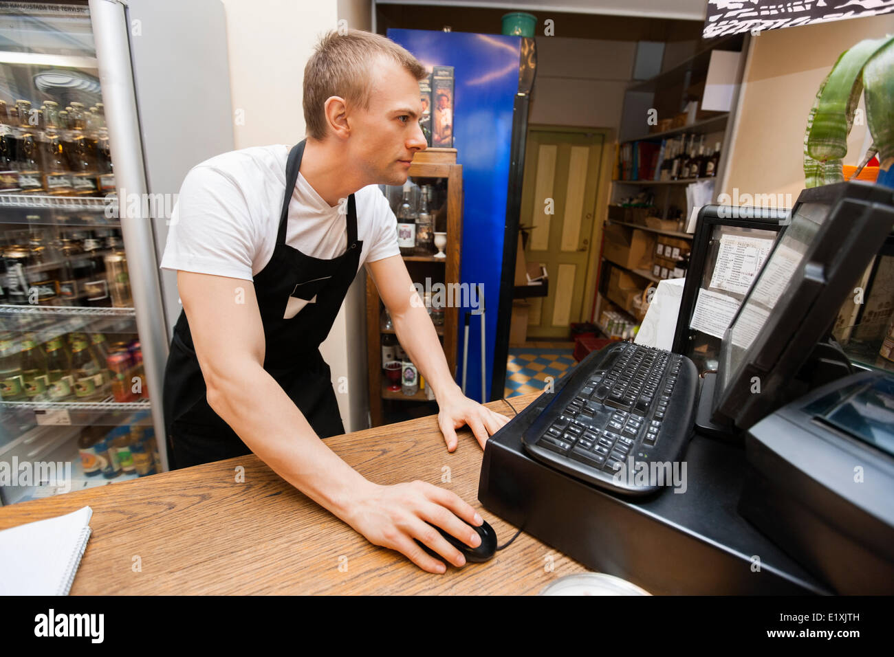 Portrait of salesman using computer at cash counter in supermarket