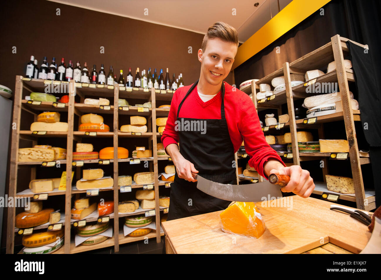 Portrait of confident male salesperson cutting cheese in store Stock Photo