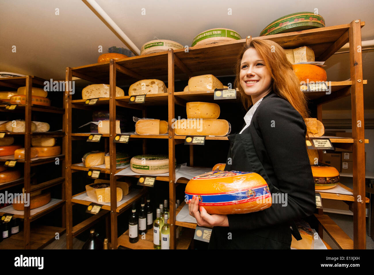 Side view of female salesperson holding cheese in store Stock Photo