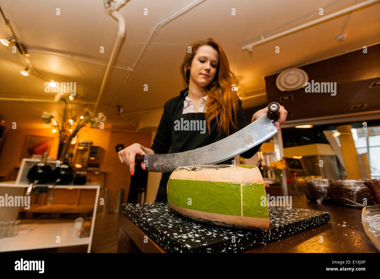 Female salesperson cutting cheese at store Stock Photo