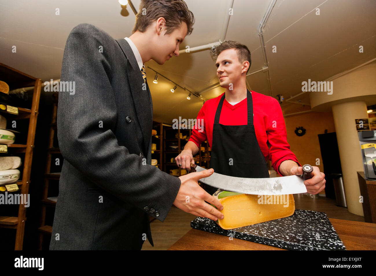 Young store clear cutting cheese for businessman Stock Photo