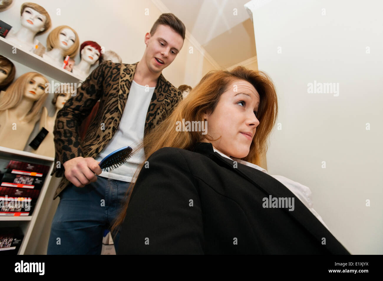Male hairstylist brushing female customer's hair in salon Stock Photo