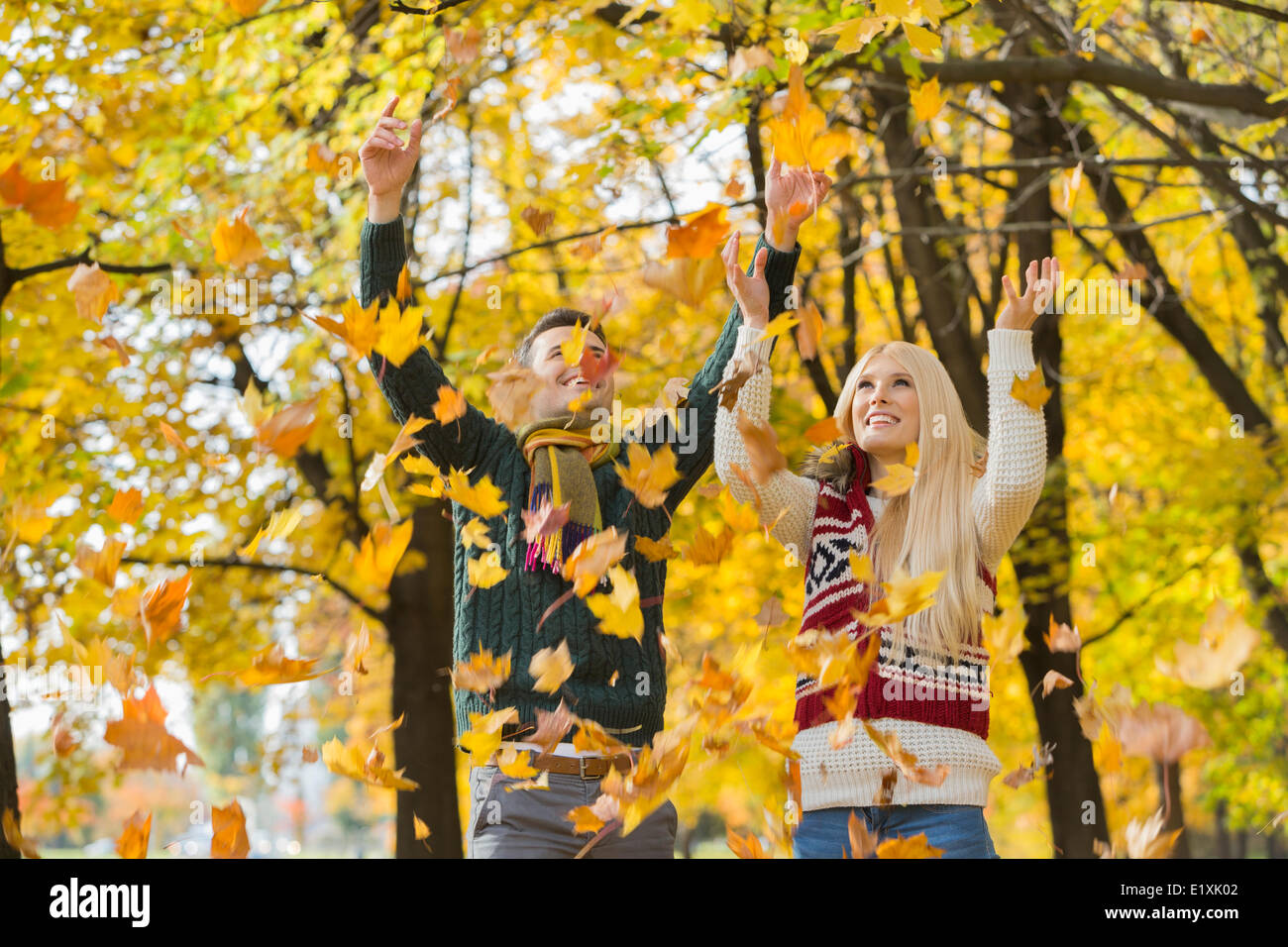 Young couple enjoying falling autumn leaves in park Stock Photo - Alamy