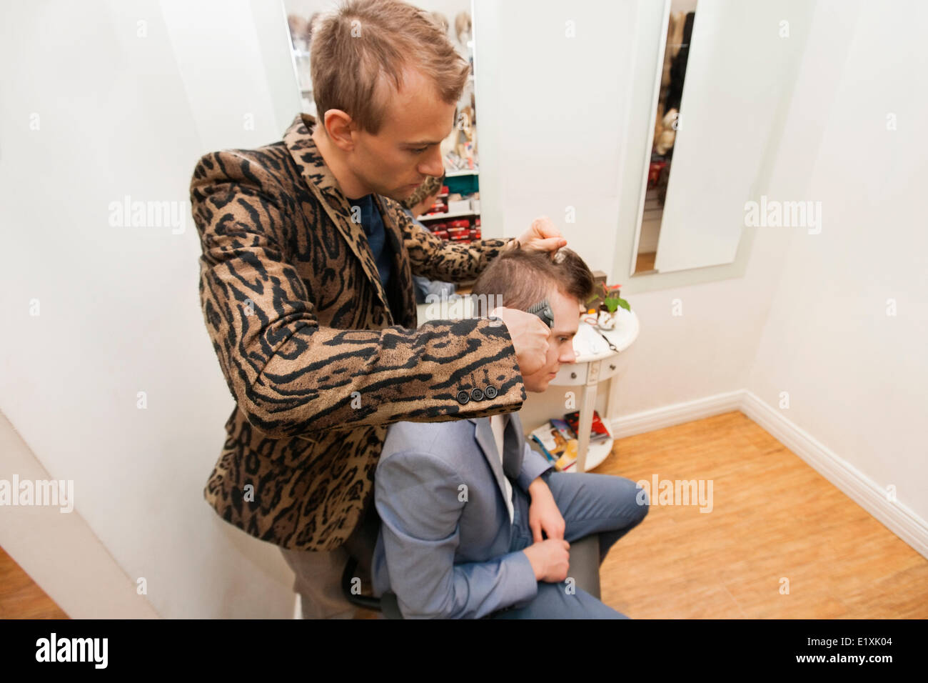 Professional barber shaving male customer's hair in shop Stock Photo