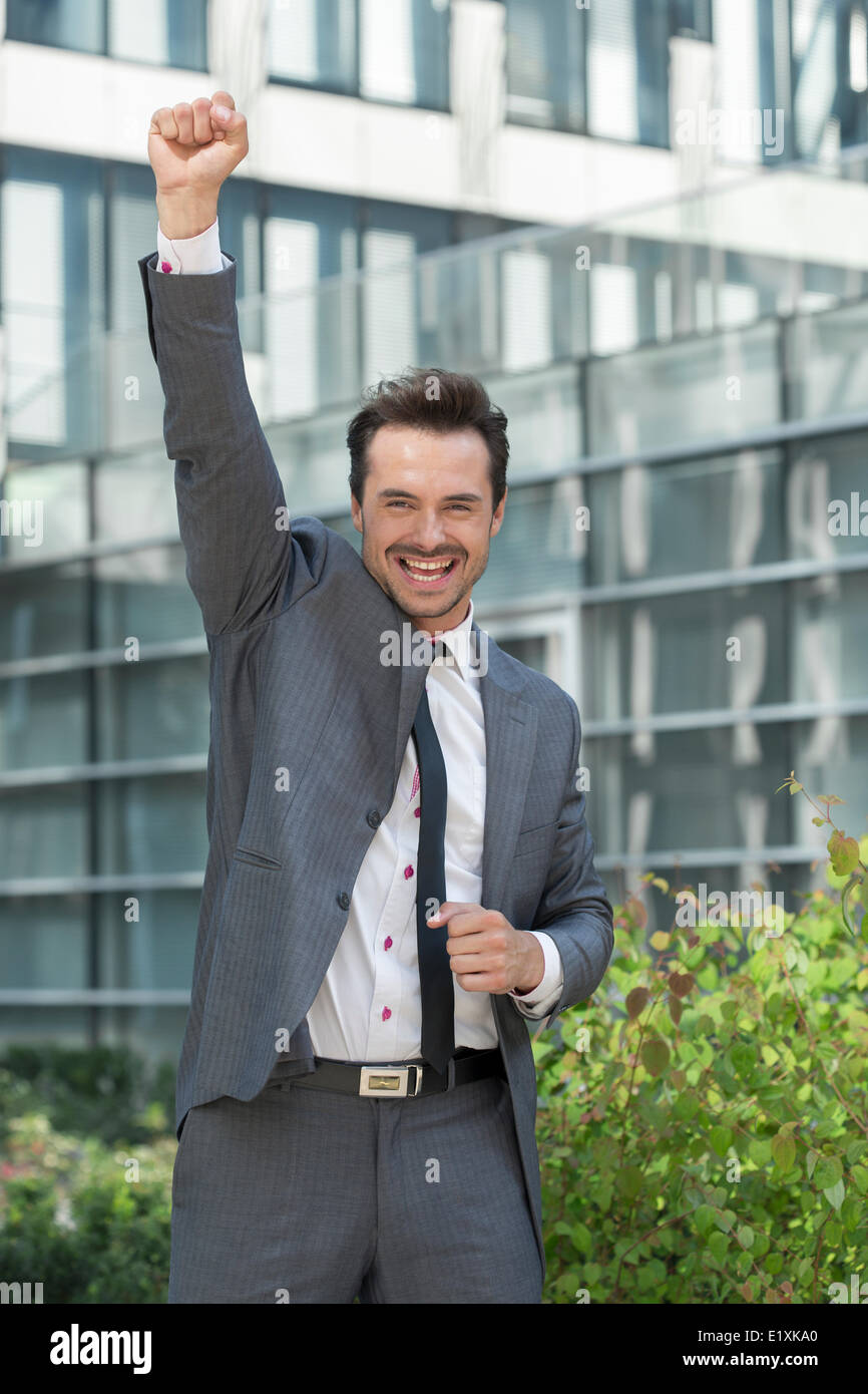 Portrait of excited businessman with arm raised celebrating success ...