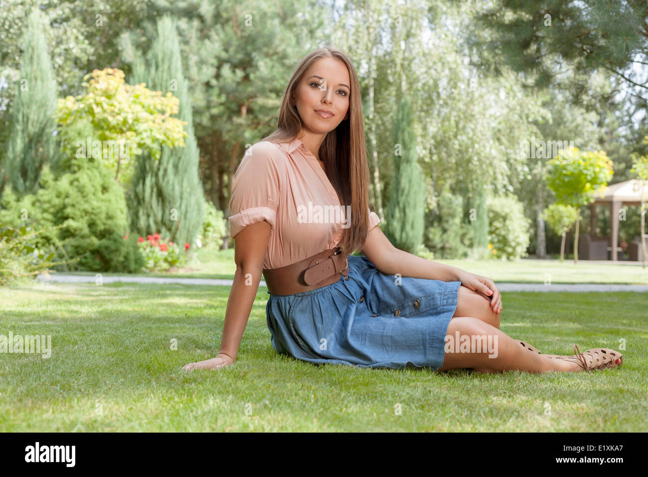 Portrait of attractive young woman sitting on grass in park Stock Photo ...