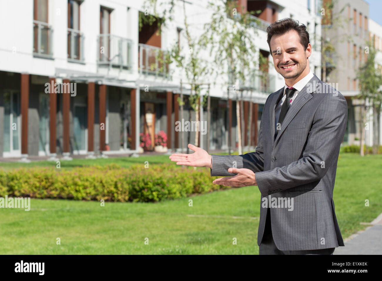 Portrait of happy real estate agent presenting office building Stock Photo