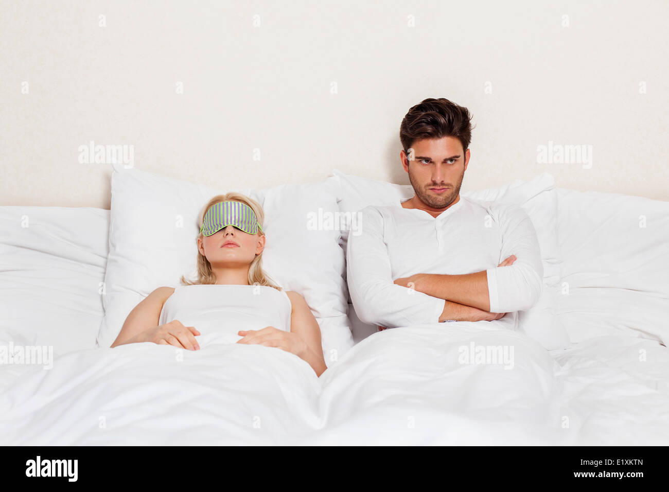 Displeased young man with woman sleeping in bed Stock Photo