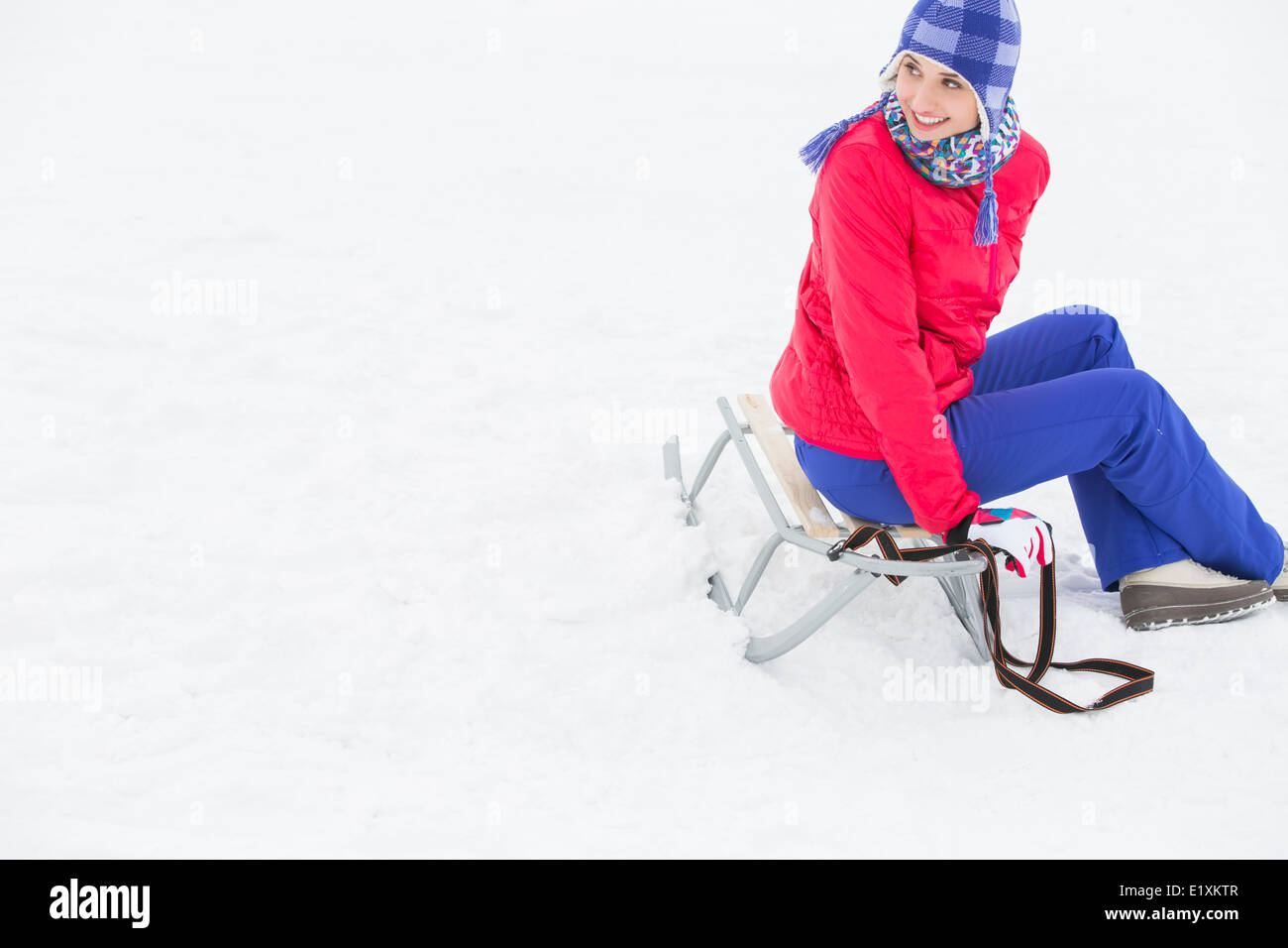 Beautiful young woman sitting on sled Stock Photo
