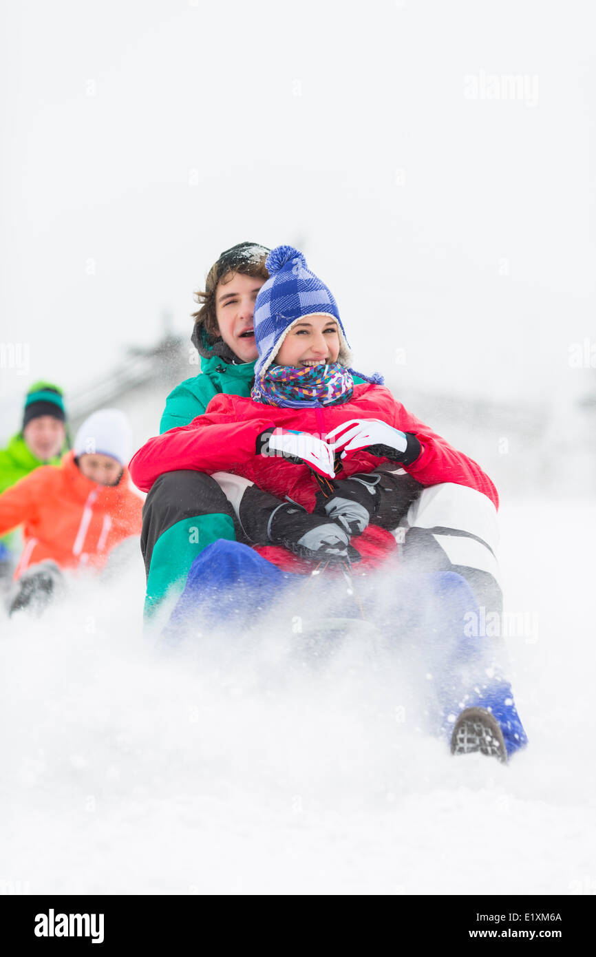 Excited young friends sledding in snow Stock Photo