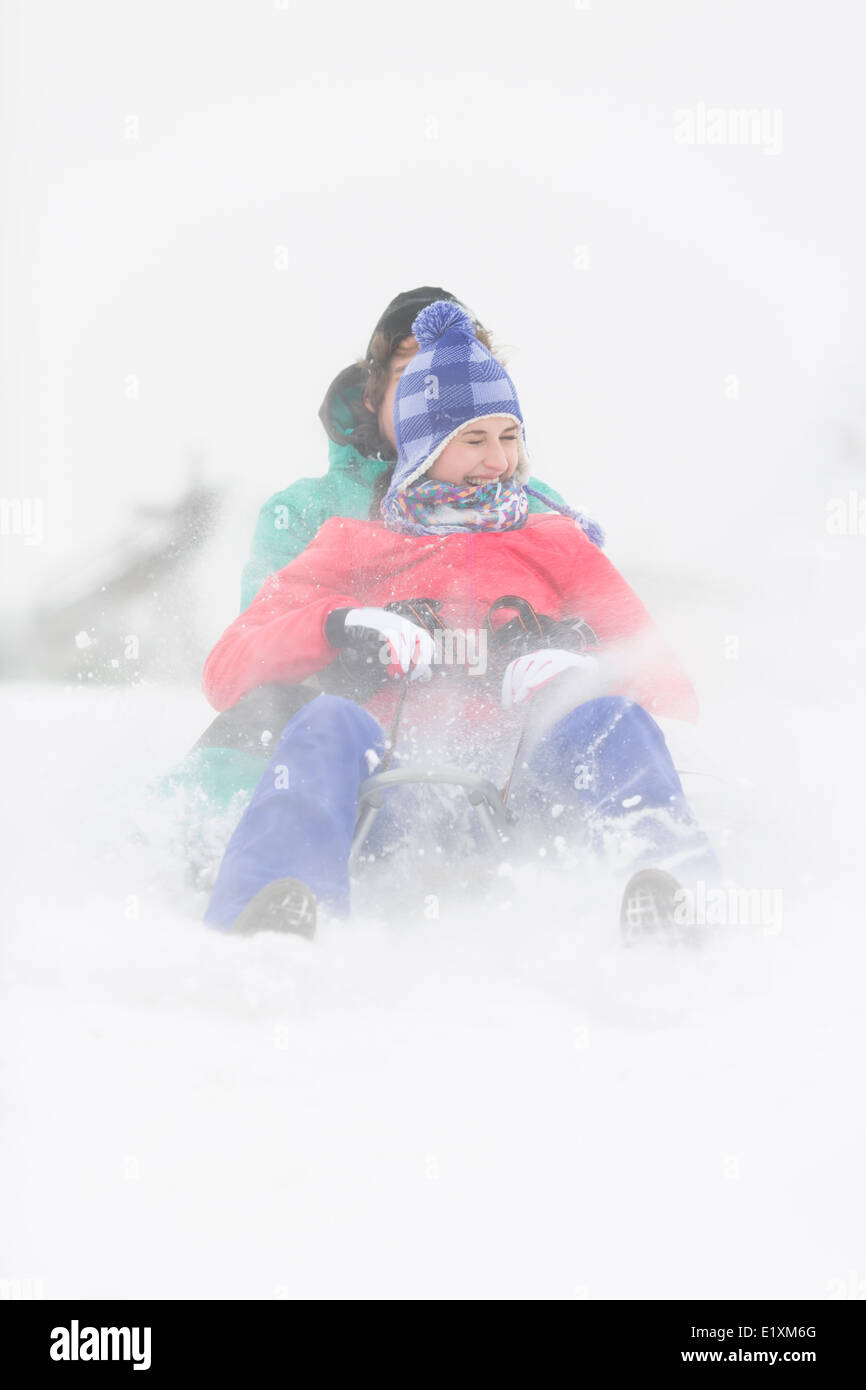 Cheerful young couple sledding in snow Stock Photo