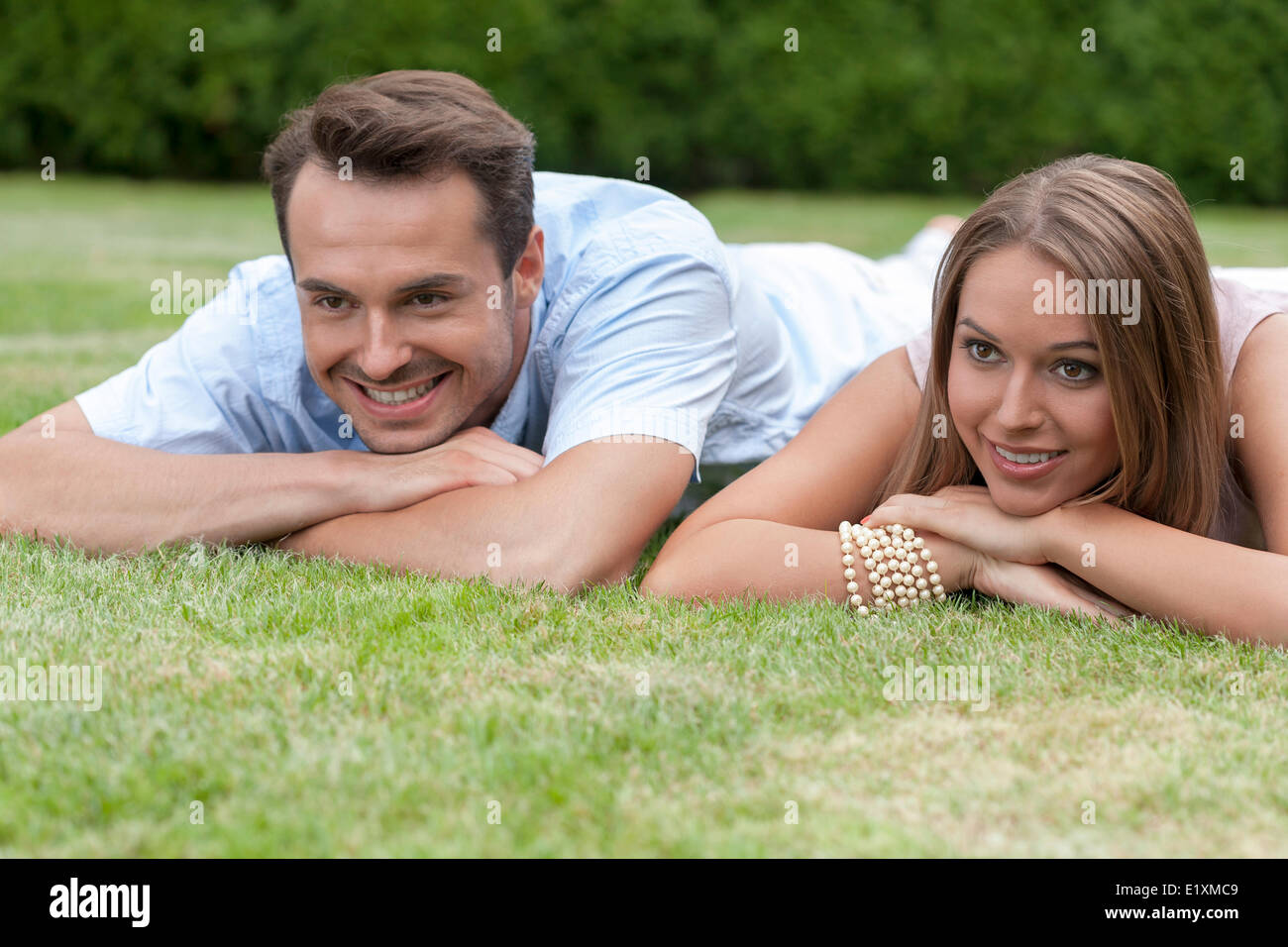 Smiling young couple lying on grass Stock Photo - Alamy
