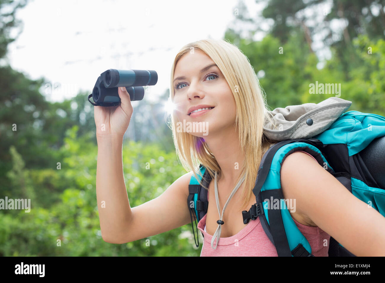 Young female hiker using binoculars in forest Stock Photo