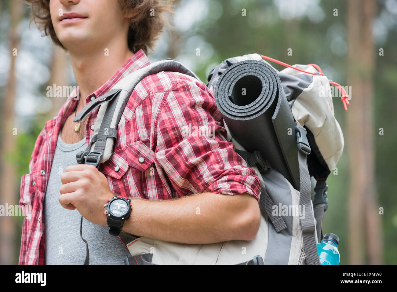 Midsection of male hiker carrying backpack in forest Stock Photo