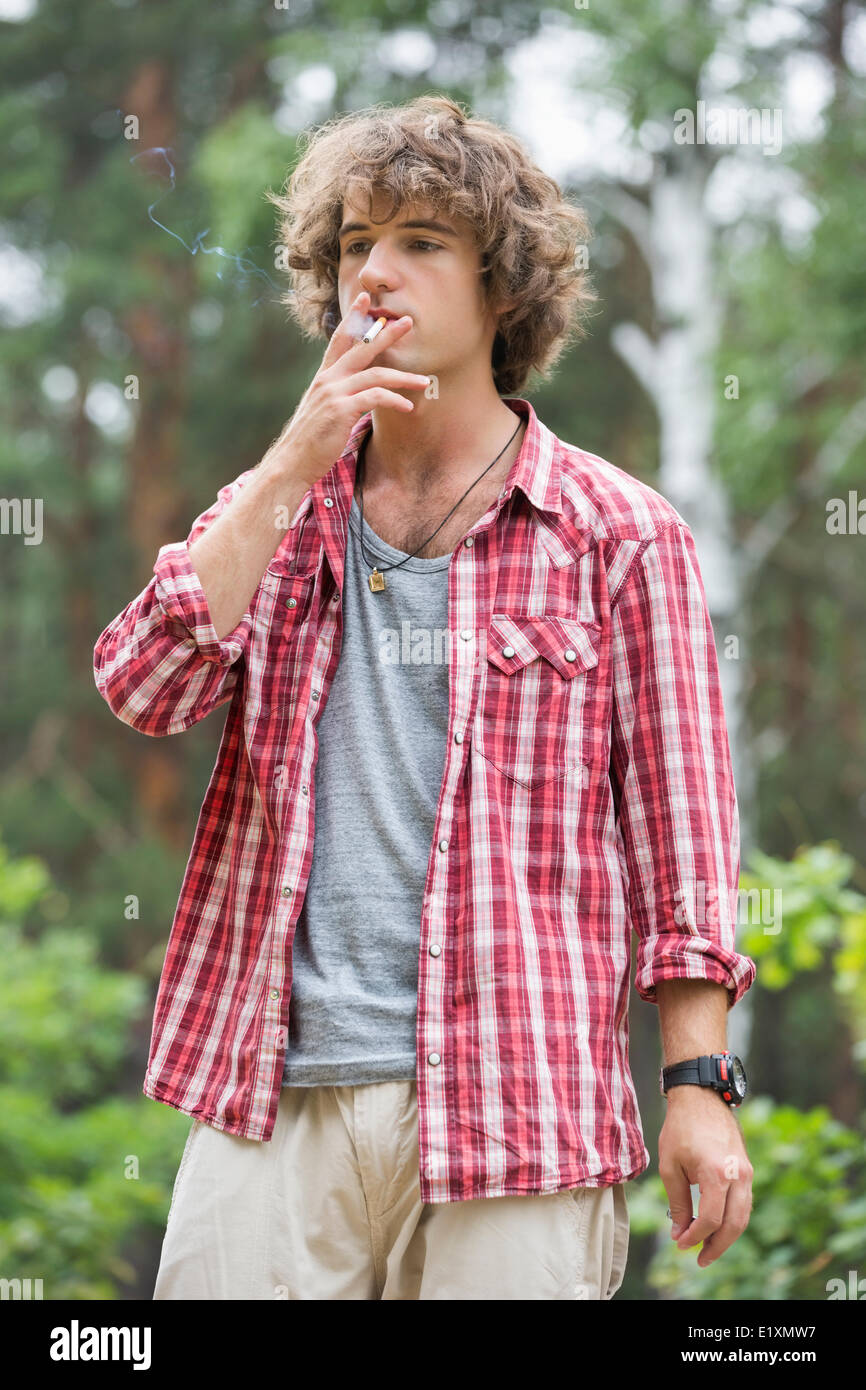 Young man smoking in forest Stock Photo