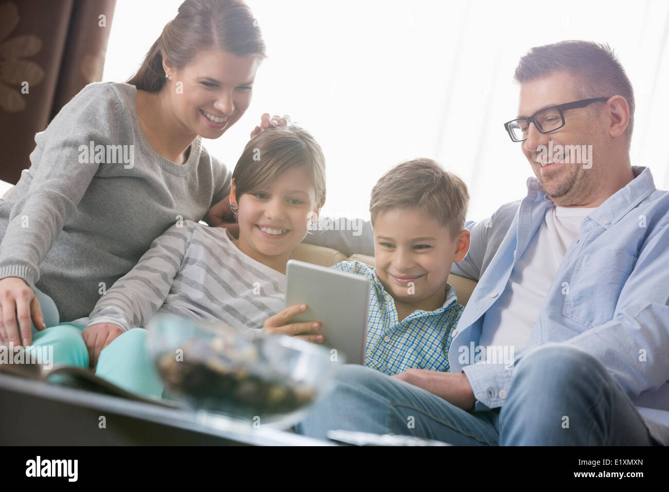 Happy family using digital tablet together in living room Stock Photo