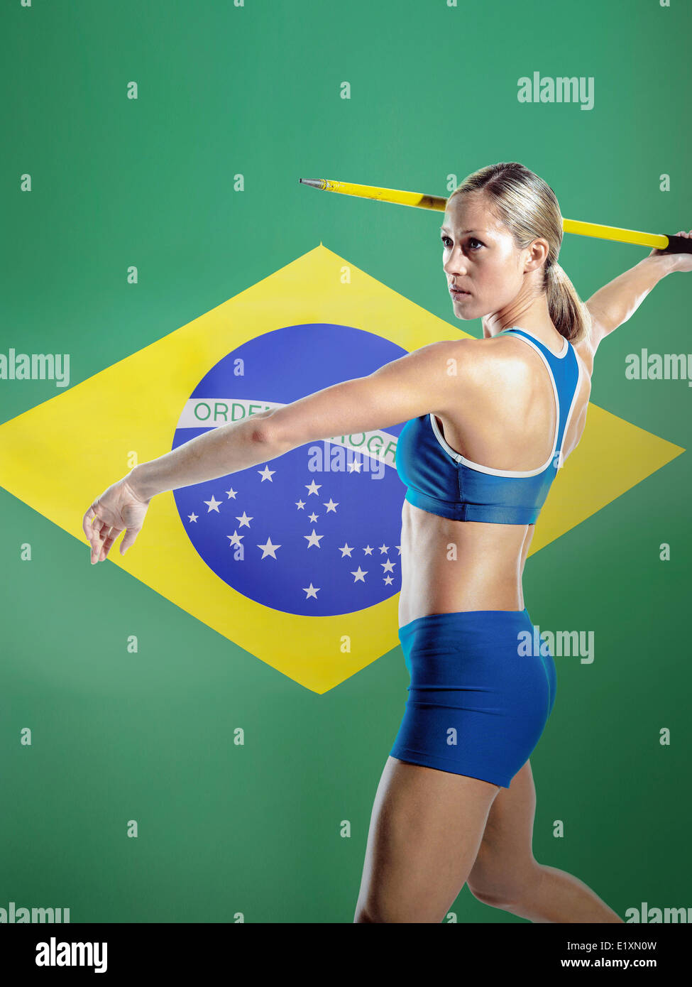 Side view of female athlete throwing javelin against Brazilian flag Stock Photo