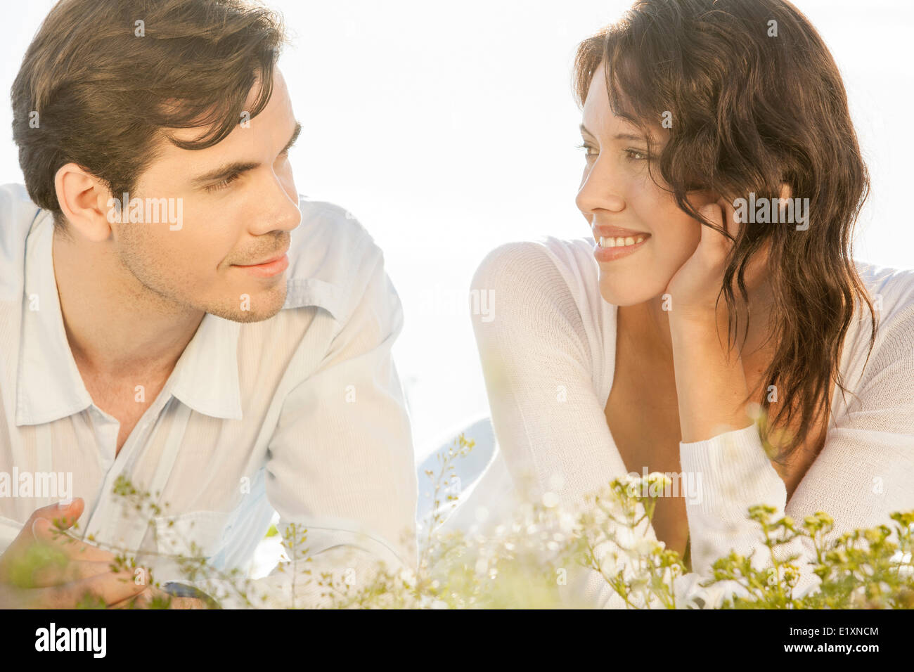 Loving couple looking at each other while lying against clear sky Stock Photo
