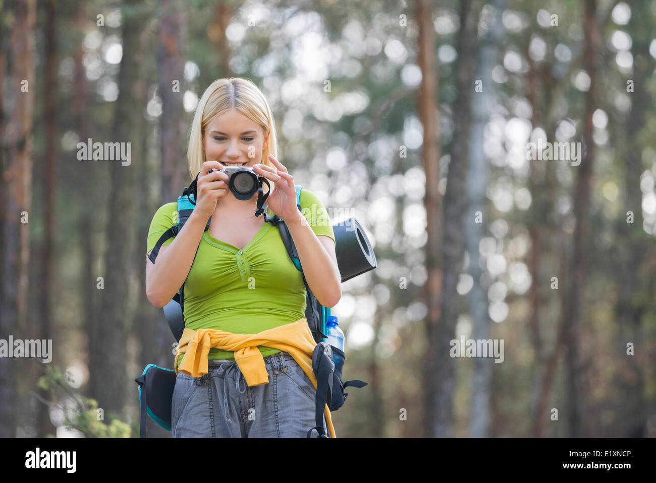 Female hiker photographing through digital camera in forest Stock Photo