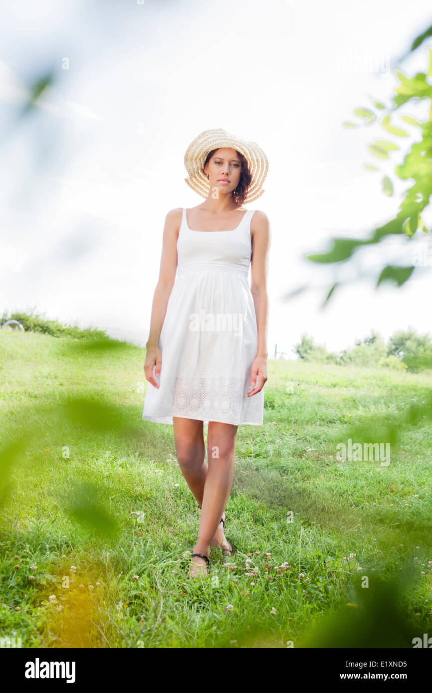 young woman in sundress and hat walking 