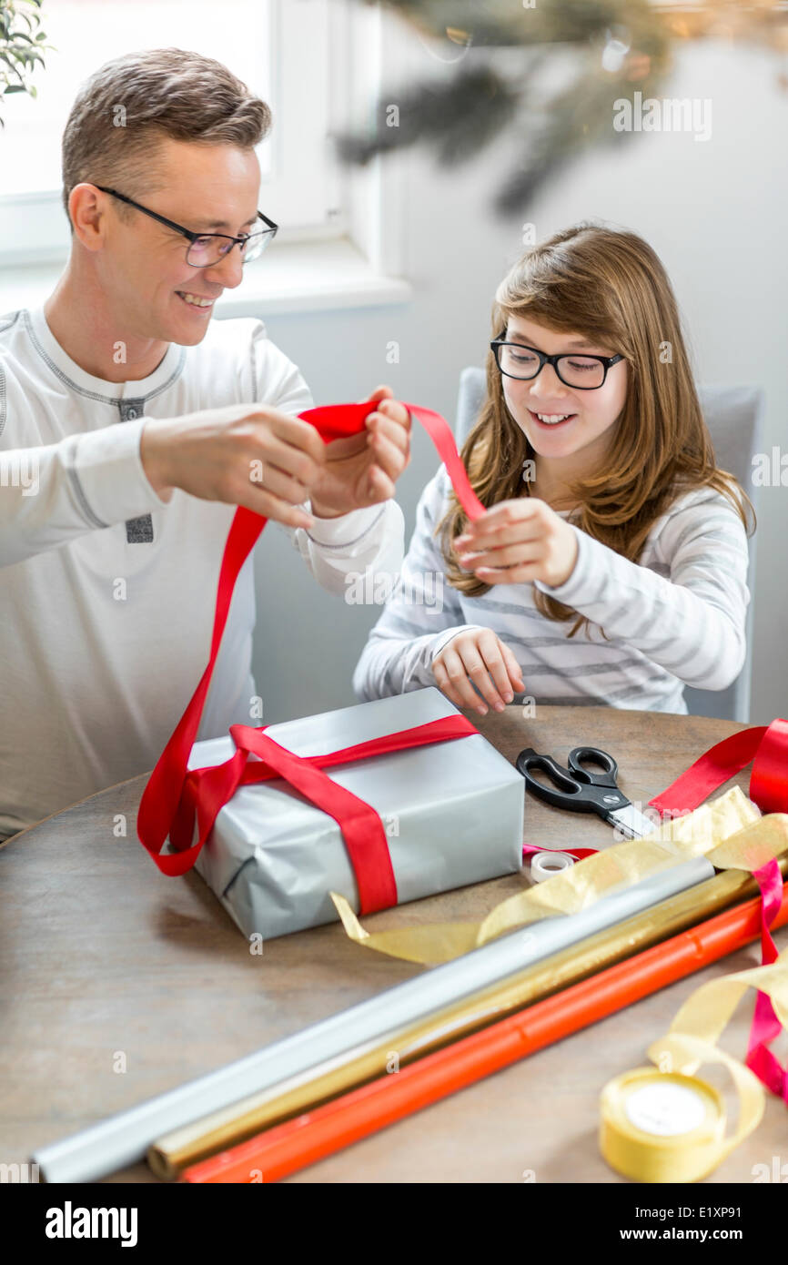 Happy father and daughter wrapping Christmas present at home Stock Photo