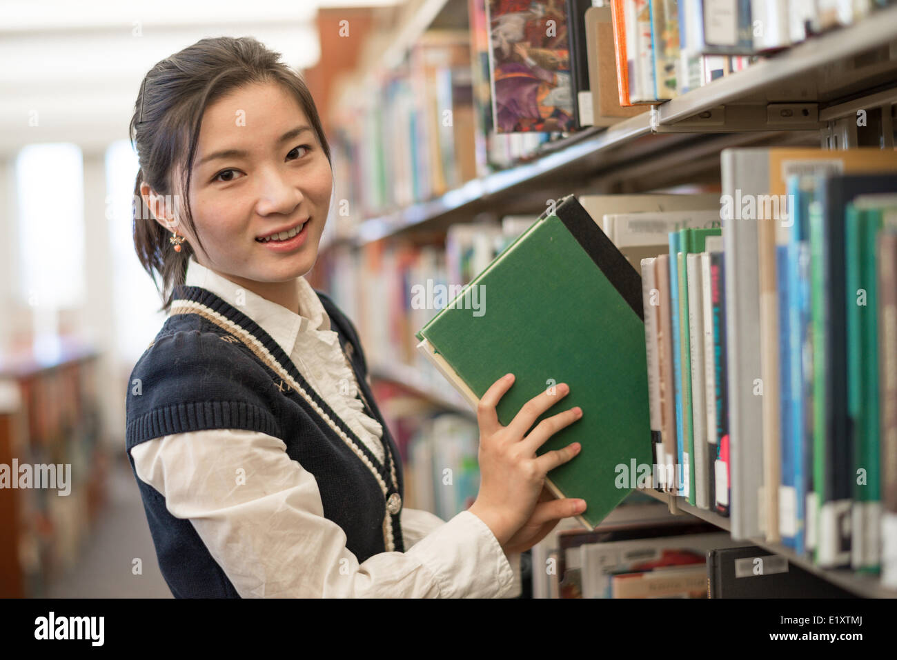 Woman putting book back onto a bookshelf Stock Photo Alamy
