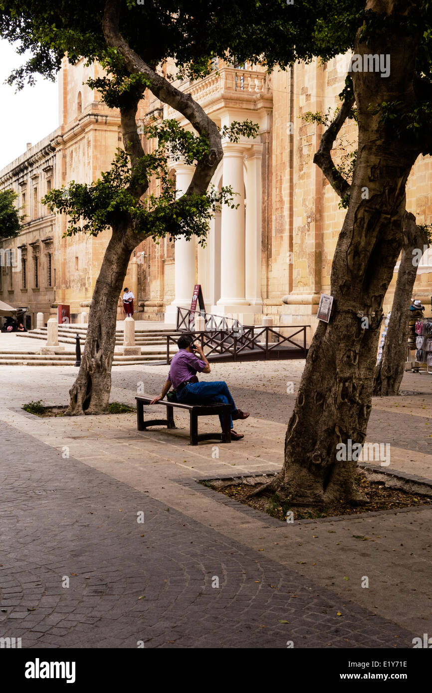 Tourist sitting on a bench, using a mobile phone.Man fifties. Stock Photo