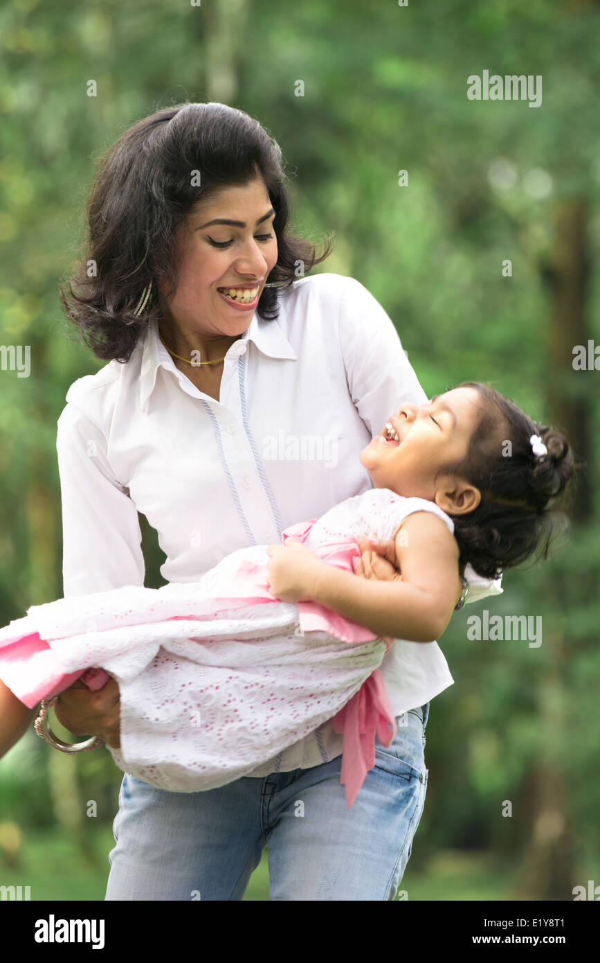 indian mother carrying daughter playing in outdoor park Stock Photo