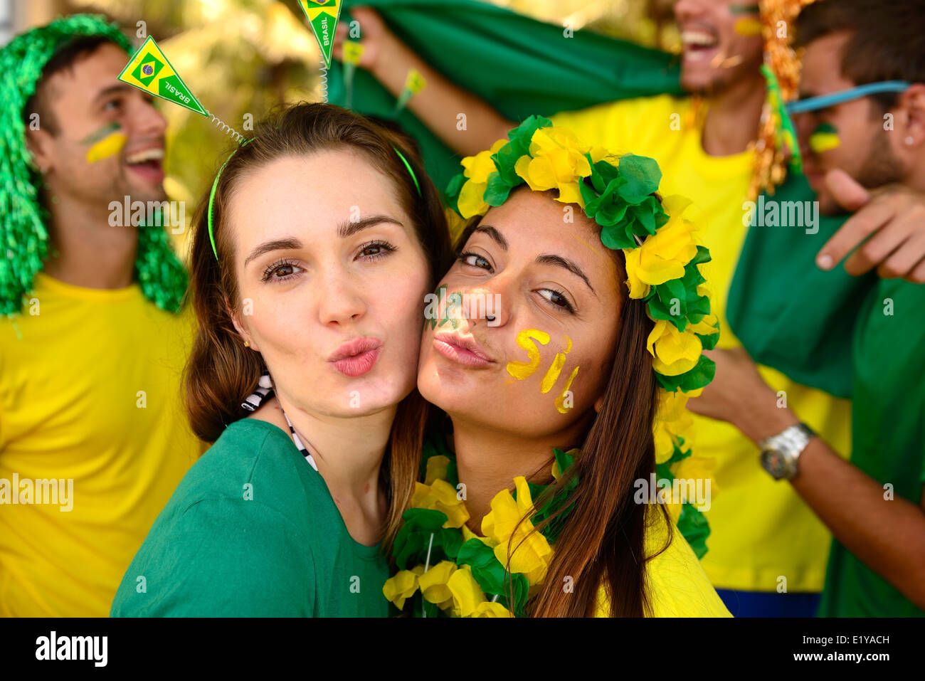 Group of Brazilian girls soccer fans commemorating victory posing kissing. Stock Photo