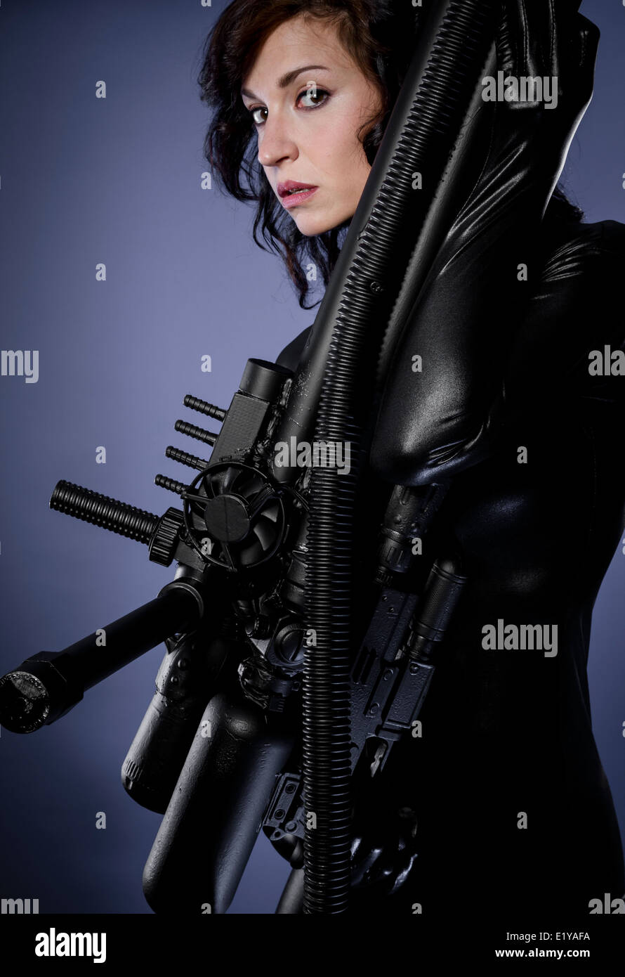 Futuristic woman in black latex dress, machine gun Stock Photo Alamy
