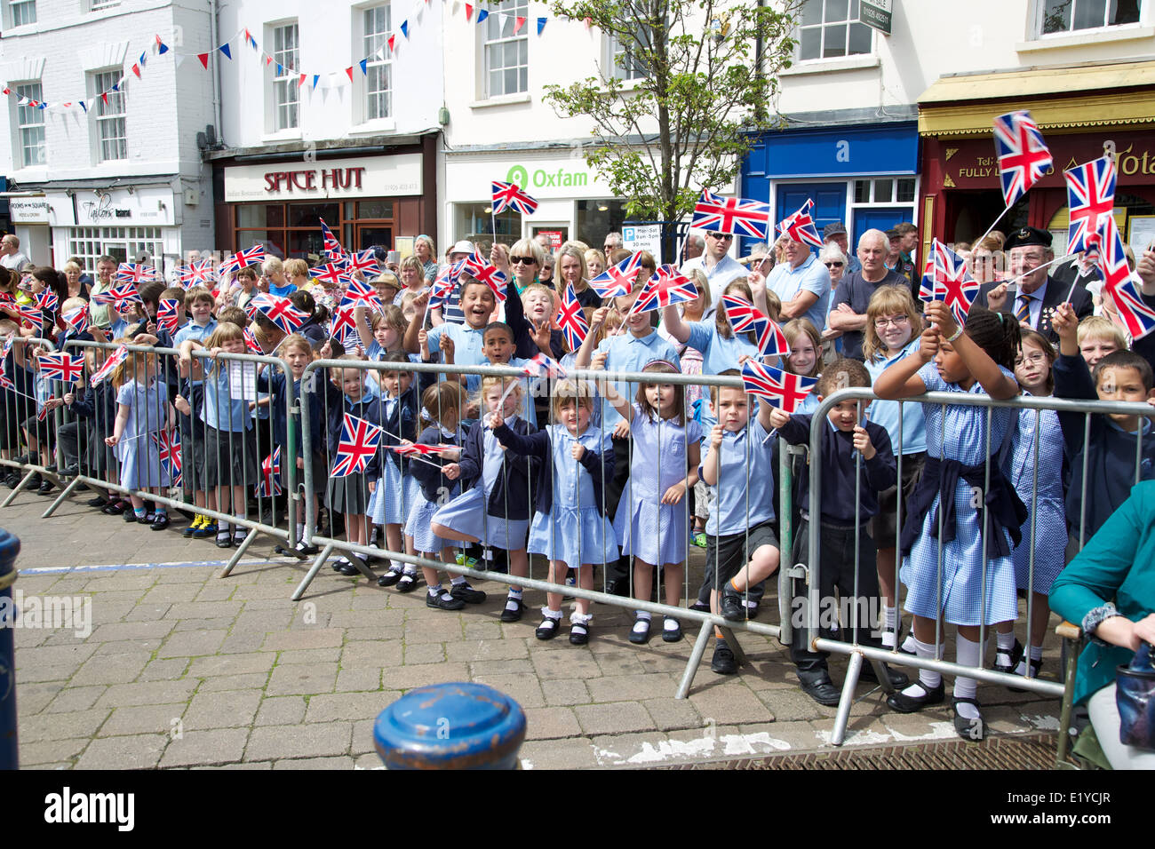 Crowd of happy school children waving union jack flags at a street parade in Warwick Stock Photo