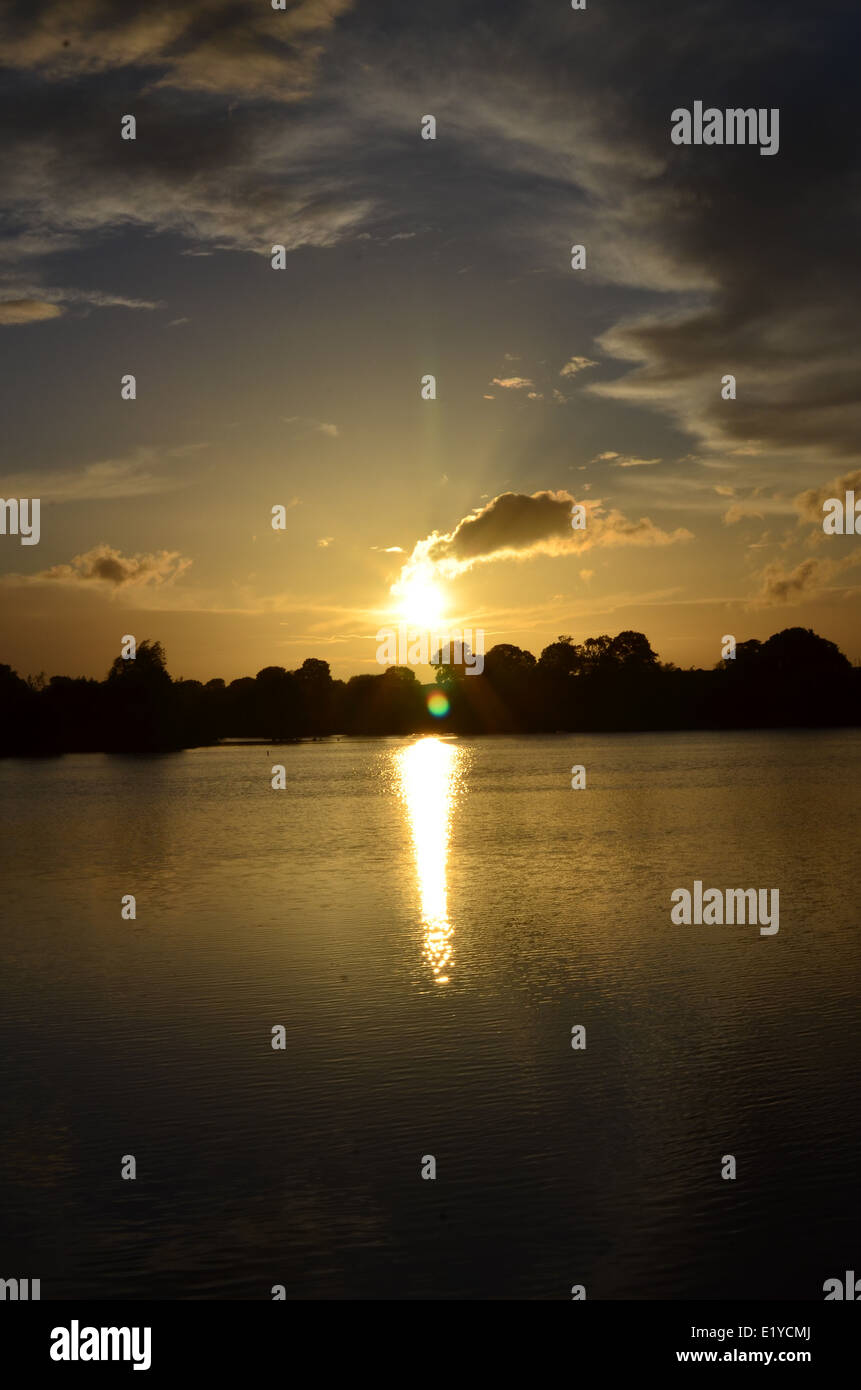 sun set over water withe reflection with storm and white clouds and ...