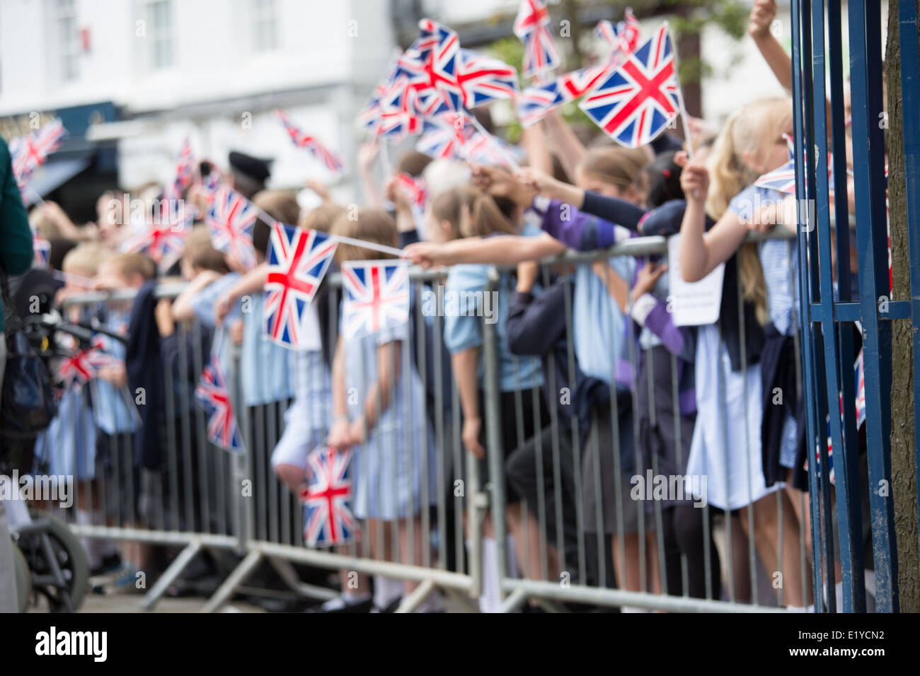 A crowd of schoolchildren waving union jack flags at a parade Stock Photo