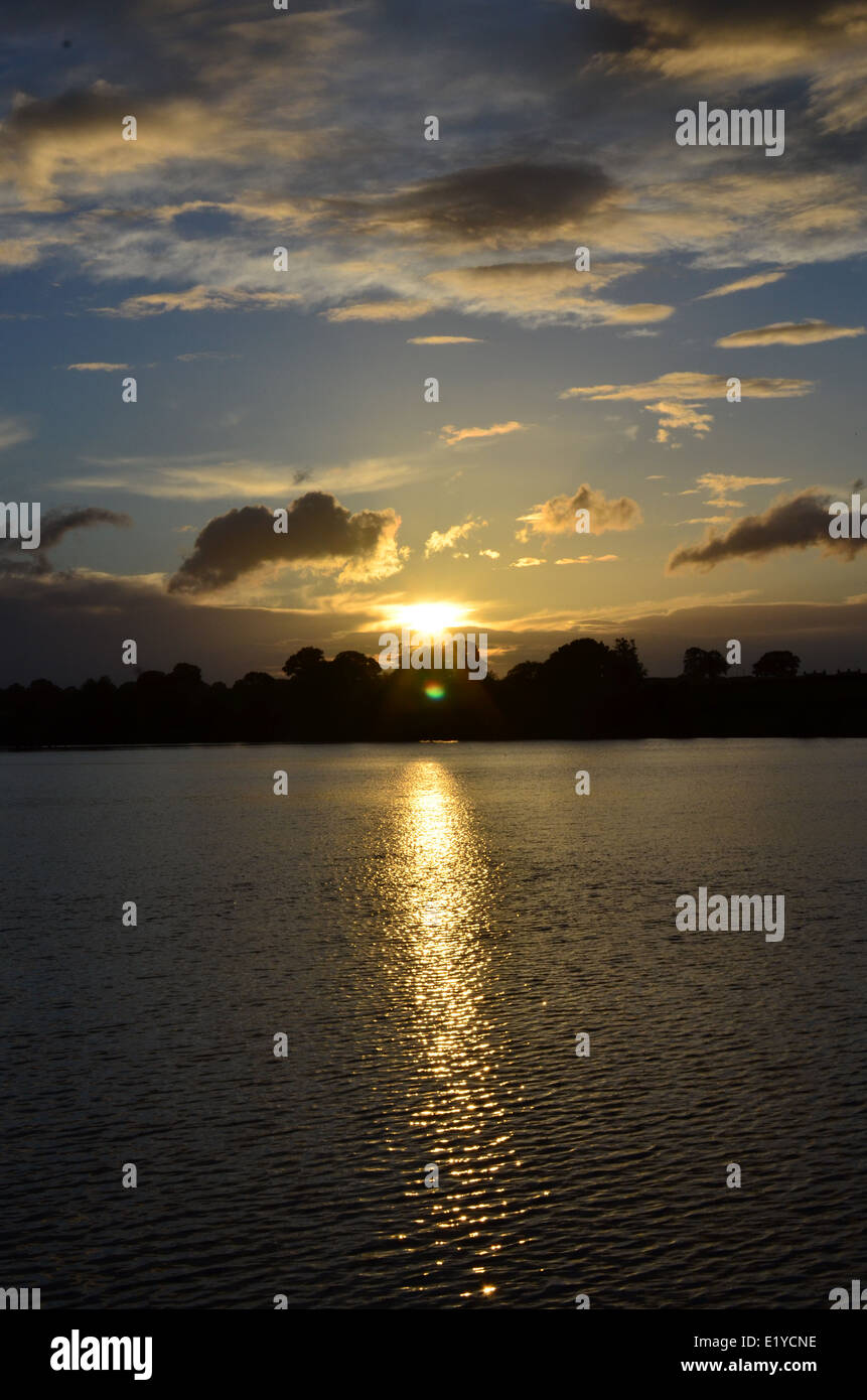 sun set over water withe reflection with storm and white clouds and ...