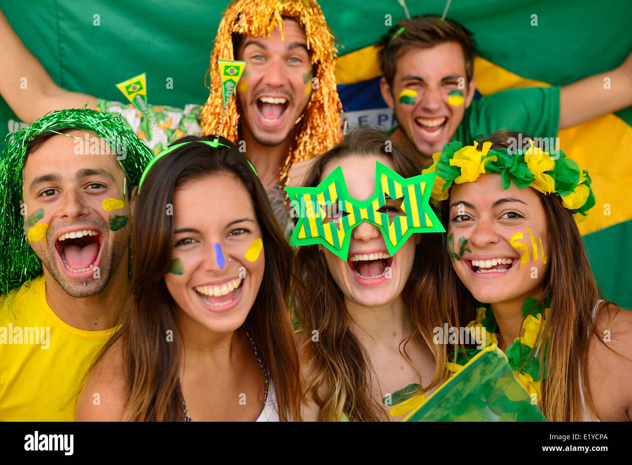 Happy group of Brazilian sport soccer fans amazed celebrating victory together. Stock Photo