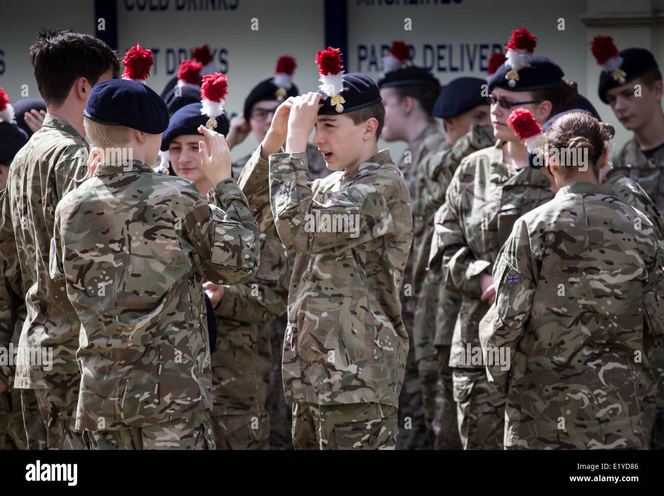 A group of young army cadets adjust their uniforms as they prepare for a military parade in