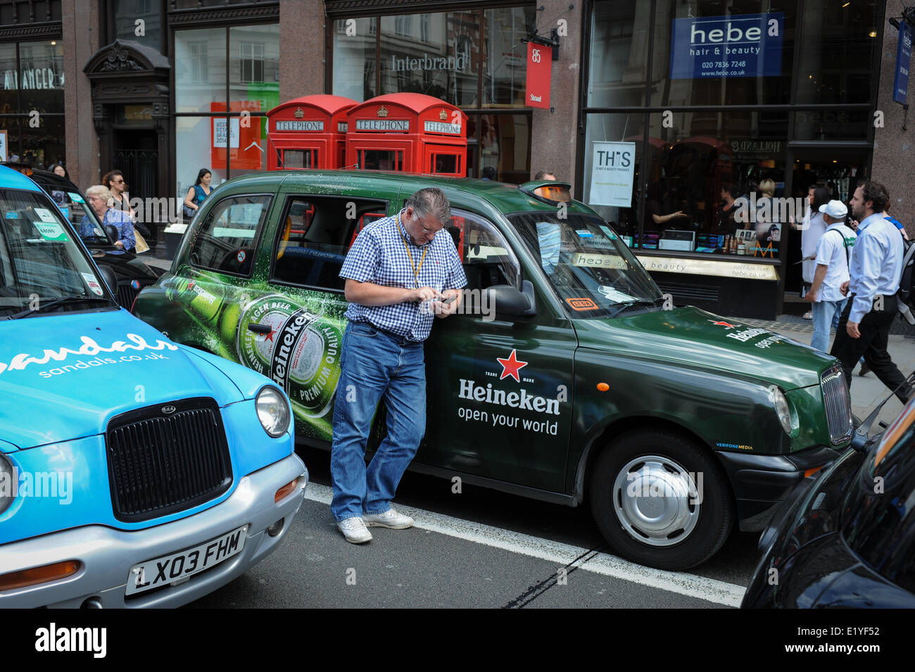 A taxi driver checks his phone after blocking the Strand in London