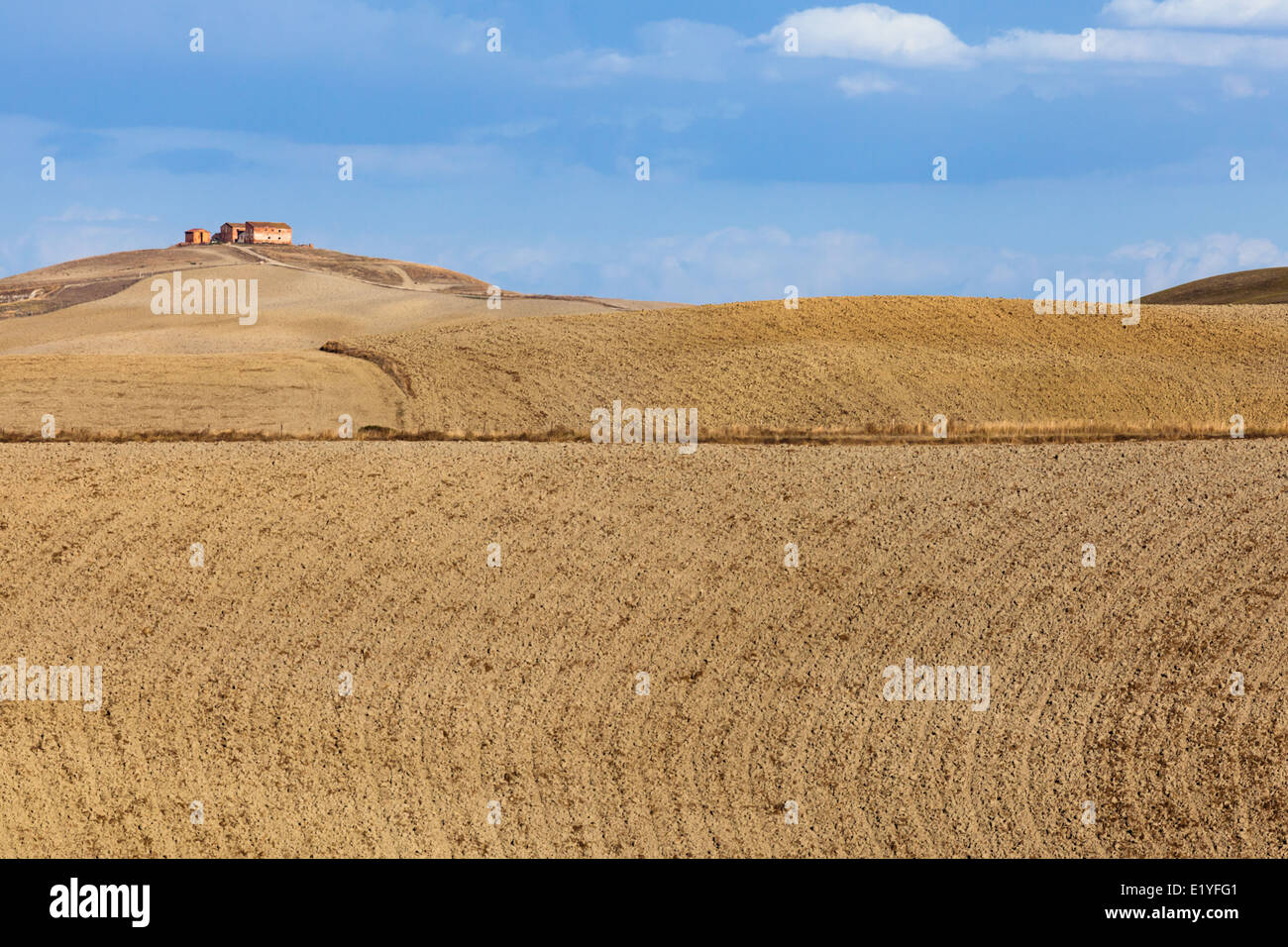 Landscape with buildings on the hill and ploughed land in region of Mucigliani (between Siena and Asciano), Tuscany, Italy Stock Photo