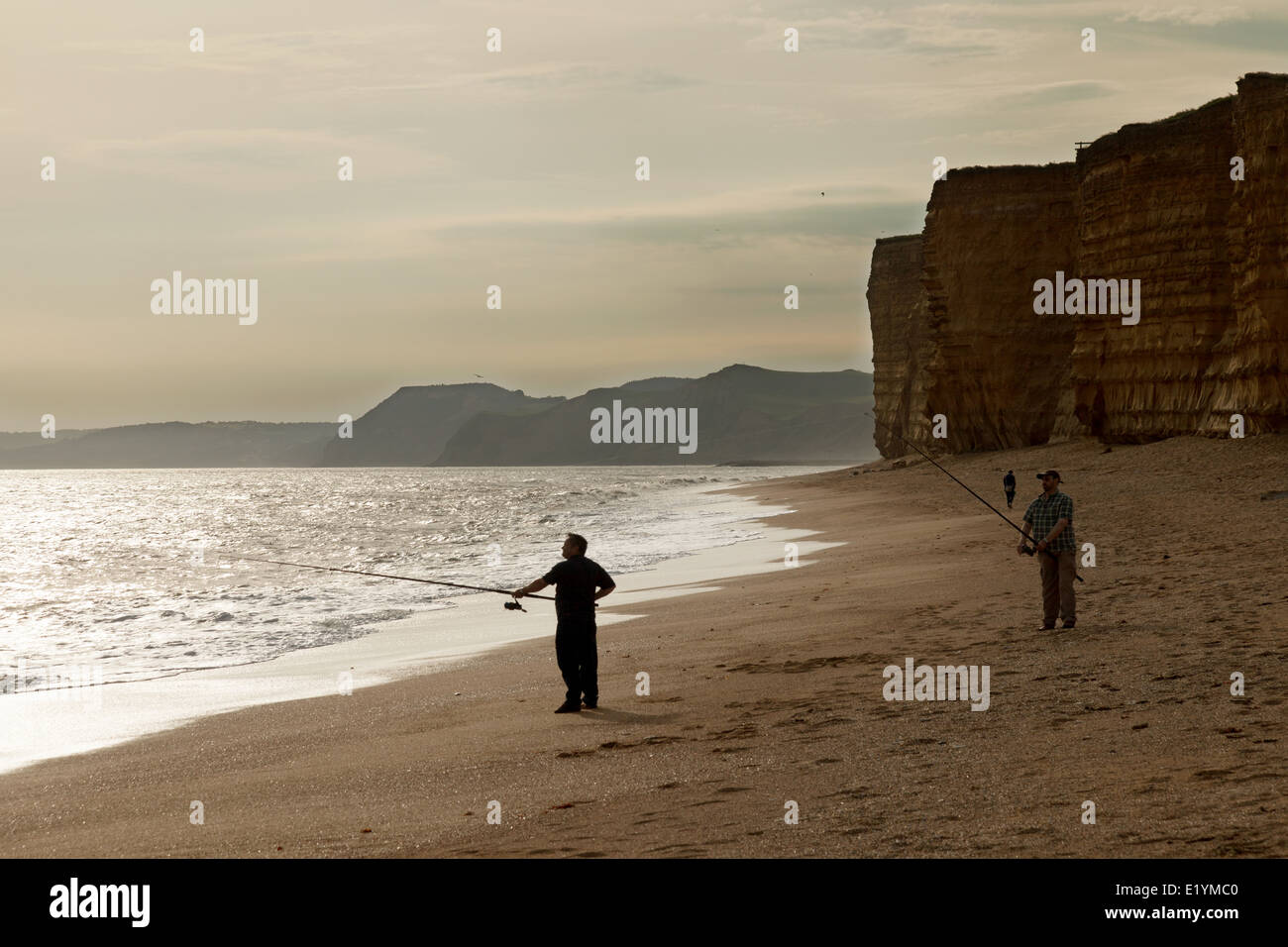 People fishing on the beach at sunset, Hive Beach, the Jurassic Coast, Dorset England UK Stock Photo