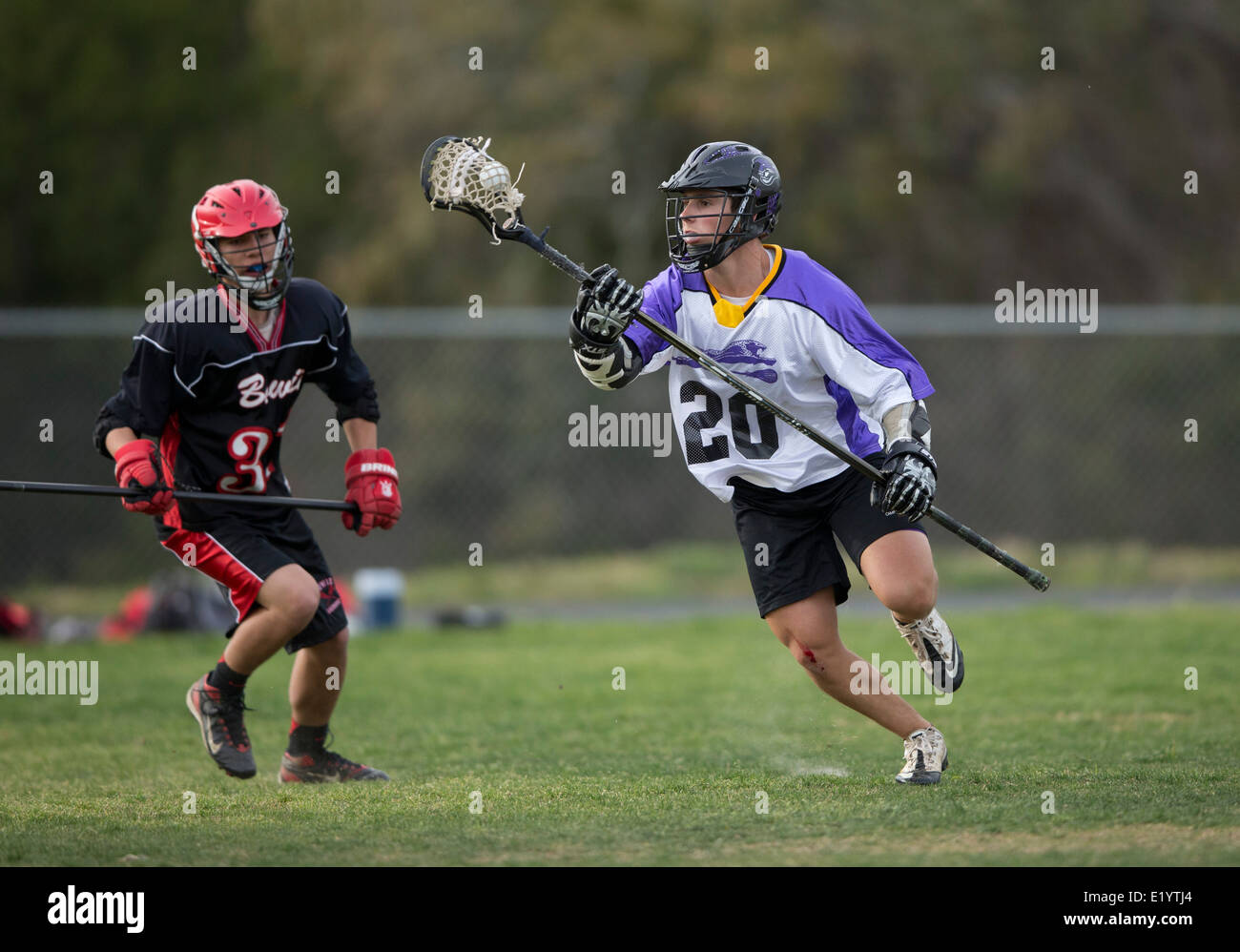 High school boys wear helmets while competing in a varsity lacrosse
