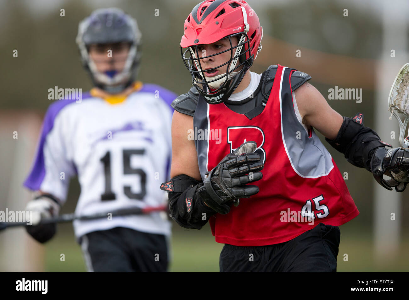 High school boys wear helmets while competing in a varsity lacrosse