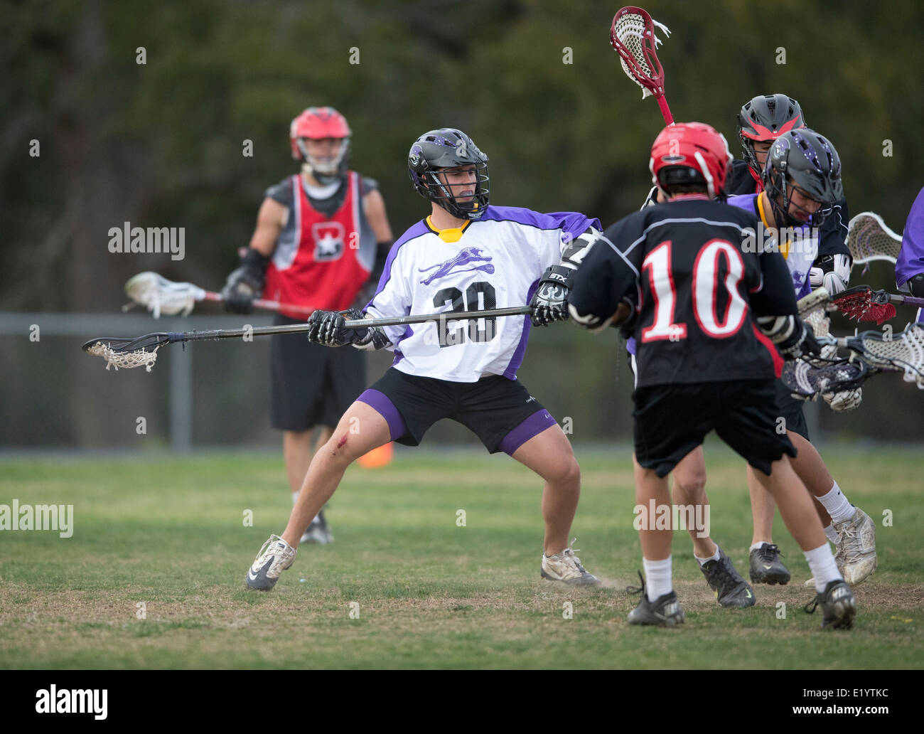 High school boys wear helmets while competing in a varsity lacrosse